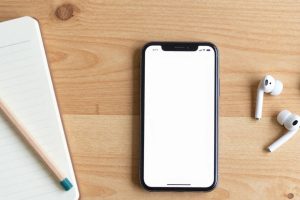 Смартфон, наушники и блокнот с калькулятором на рабочем столе